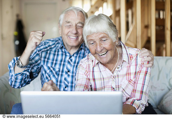 Excited senior couple looking at laptop