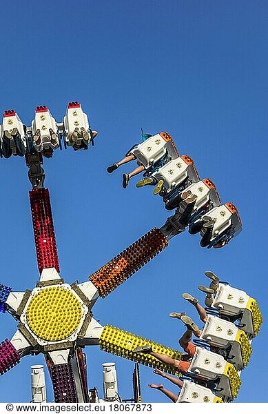 Excited thrillseekers have fun on the G Force funfair attraction at the travelling funfair