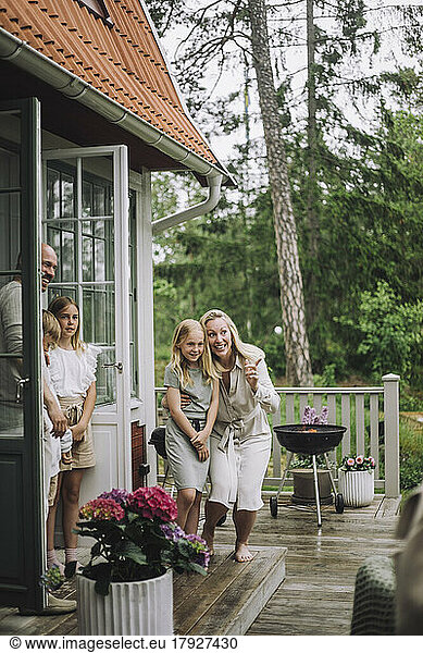 Excited woman pointing while standing with daughter on porch