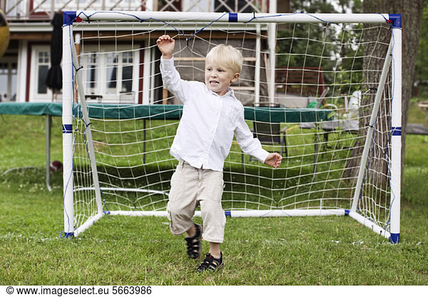 Excited young boy standing at goal post