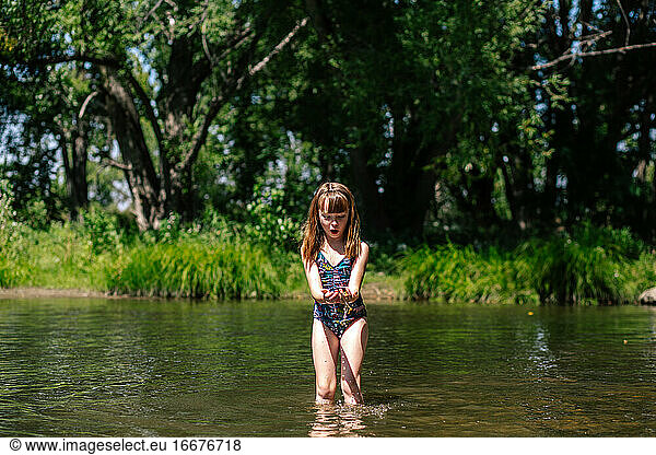 Excited young girl playing in a creek on a sunny day