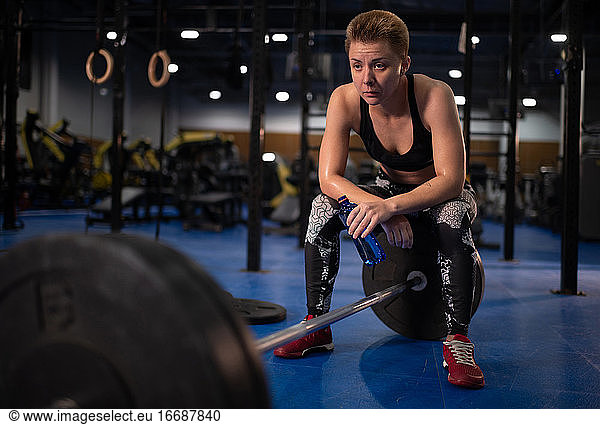 Exhausted female athlete resting during weightlifting workout