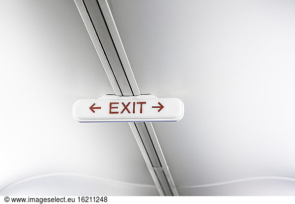 Exit sign on white airplane ceiling