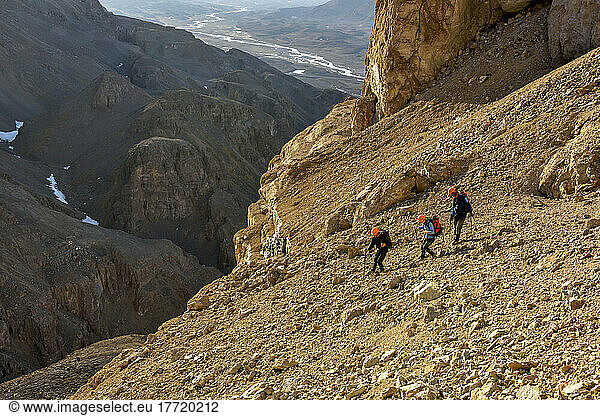 Expedition team member safely leads other team members around over the steep sectioin of scree. Grottedalen looms large in the background.