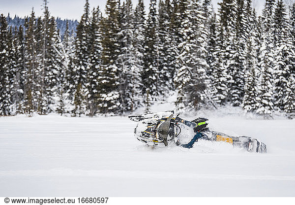 Experienced rider snowmobiling aggressively through deep snow.