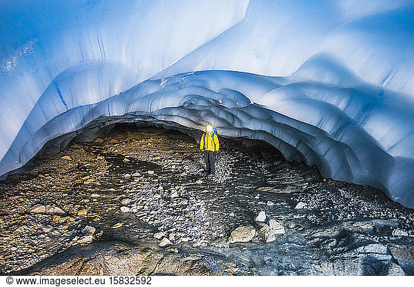 Explorer standing under glacier in cave.