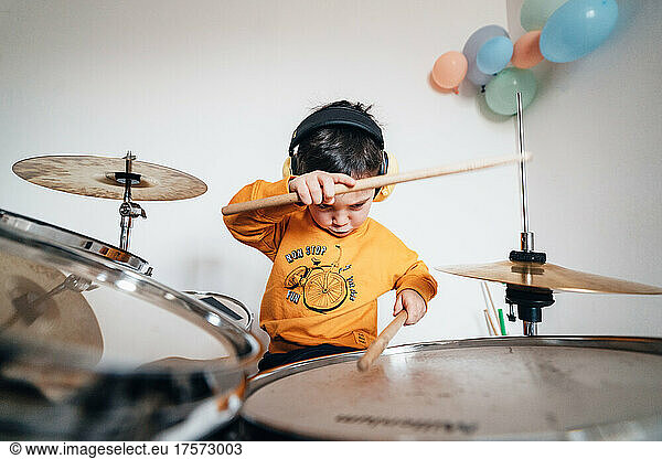 Expressive young drummer musician playing drums with drumsticks