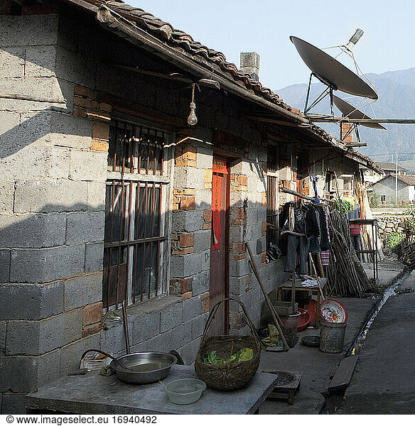 Exterior of rural house in village with satellite dish.