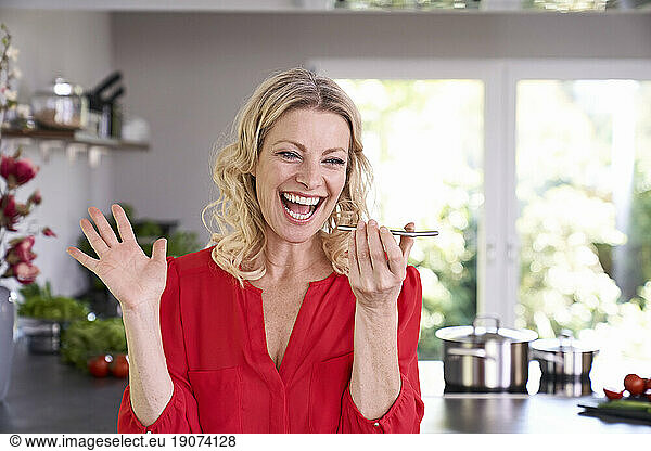 Exuberant woman using smartphone in kitchen