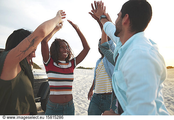 Exuberant young friends high-fiving on beach