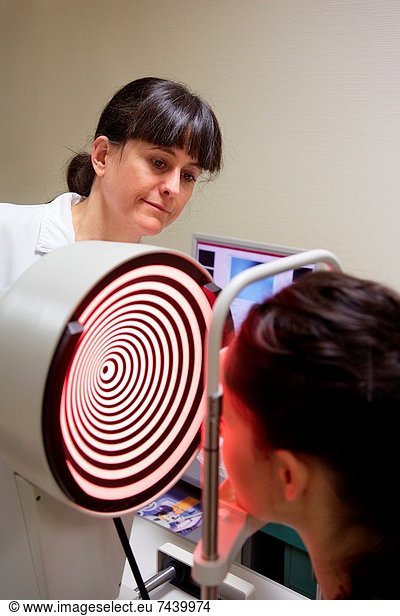 Eye examination Patient having a corneal topography measurement made of her eye The device at centre projects bright rings onto the eye  which are reflected in its surface By studying the reflection  an accurate model can be built up of the shape of her cornea The cornea is the front part of the eye that covers the iris and pupil It is responsible for the majority of light focusing  with only fine focusing being done by the lens Defects in the shape of the cornea can lead to a wide range of focusing disorders These can be treated by surgery or by the wearing of tailored contact lenses or spectacles Ophthalmology  Hospital Donostia  San Sebastian  Gipuzkoa  Basque Country  Spain