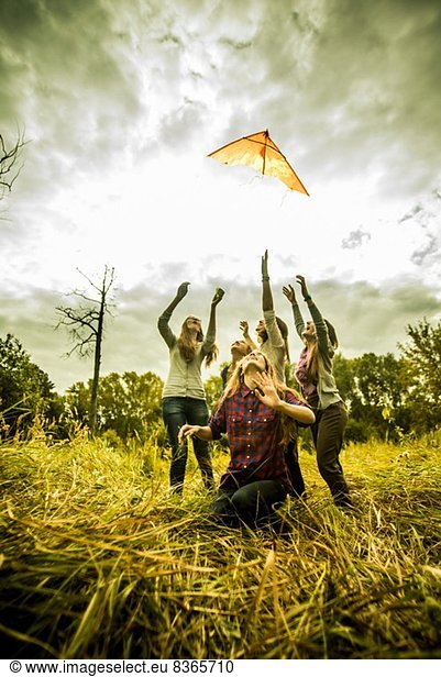 Fünf junge Frauen beim Drachenfliegen im Buschland