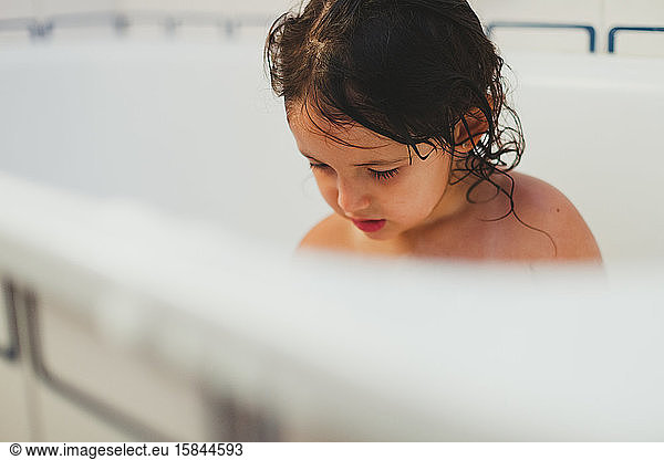 Face of little girl showering in bathtub
