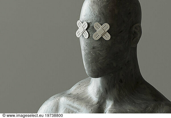 Face of mannequin with band aid eyes against gray background