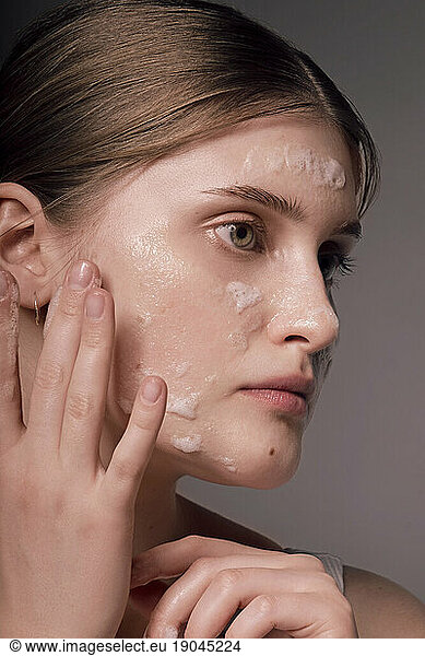 Face skin care. Woman applying a mask on clean hydrated skin portrait.