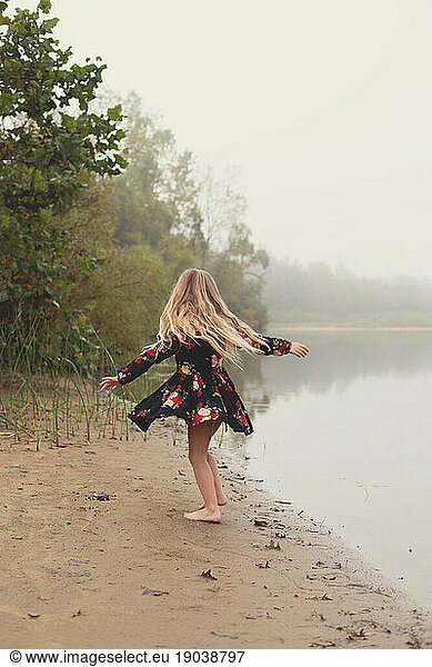 Faceless girl twirls and spins by a foggy lake