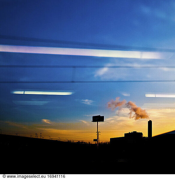 Factory seen through car window at sunset.