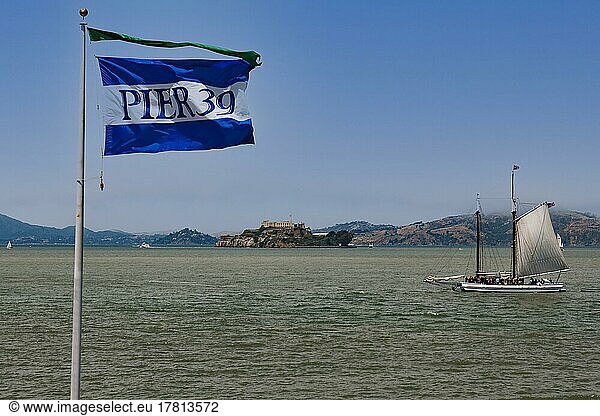 Fahne von Pier 39 und historisches Segelboot in der San Francisco Bay  hinten die Insel Alcatraz  San Francisco  Kalifornien  USA  Nordamerika