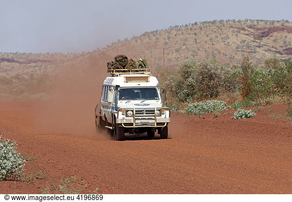 Fahrender Toyota Landcruiser FJ 75 Arkana Safari Fahrzeug mit Anhaenger auf roter Strasse in Karijini National Park Pilbara Region Westaustralien WA