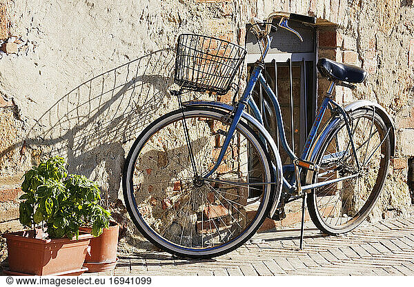Fahrrad lehnt an Steinhauswand.