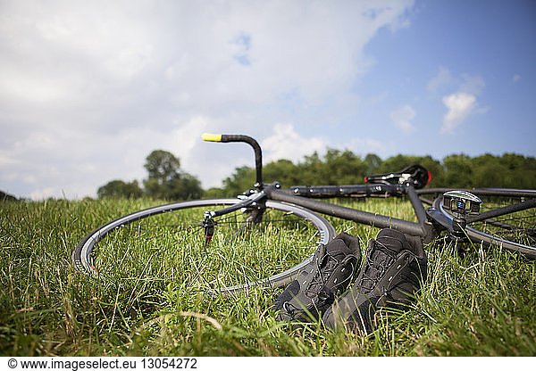 Fahrrad- und Sportschuhe auf Grasfeld gegen den Himmel