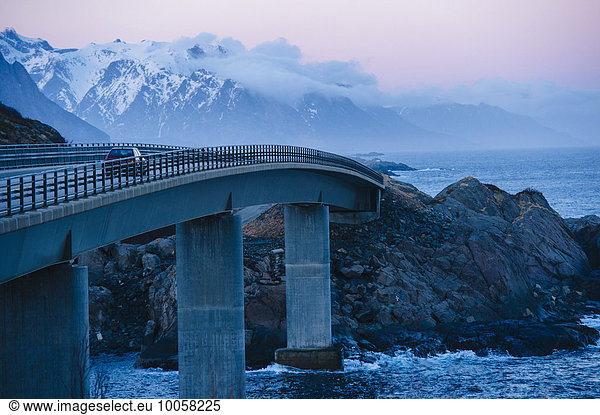 Fahrzeug über die Küstenbrücke bei Dämmerung  Reine  Lofoten  Norwegen