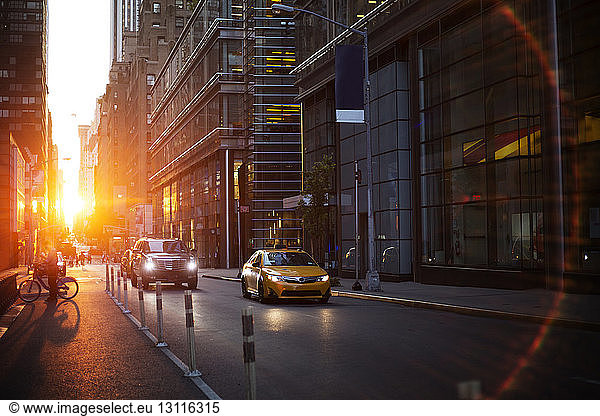 Fahrzeuge auf der Straße inmitten moderner Gebäude bei Sonnenuntergang