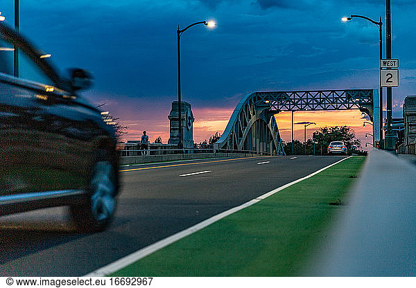 Fahrzeuge fahren bei Sonnenuntergang über die Brücke.