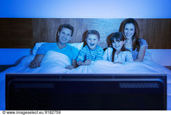Familie beim Fernsehen im Bett