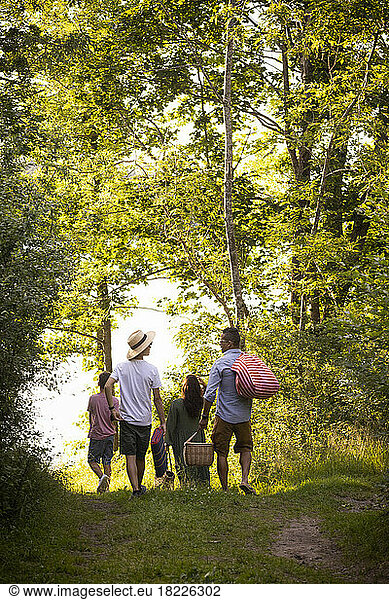 Familie beim gemeinsamen Spaziergang im Sommerurlaub im Wald