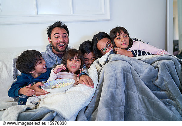 Familie kuscheln und Gruselfilm auf dem Sofa anschauen
