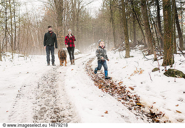 Familie mit Haushund auf Spaziergang in Schneelandschaft