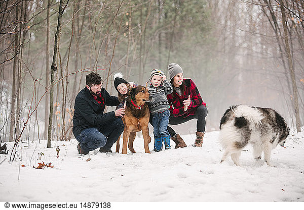 Familie mit Haushunden auf Spaziergang in Schneelandschaft