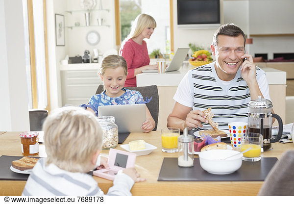 Familie mit Technik beim Frühstück