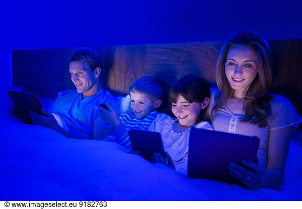 Familie mit Technik im Bett