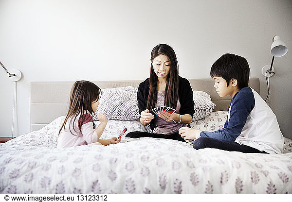 Familie spielt zu Hause im Bett Karten