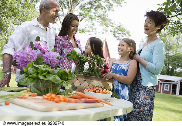 Familienfeier. Ein gedeckter Tisch mit Salaten und frischem Obst und Gemüse. Eltern und Kinder.