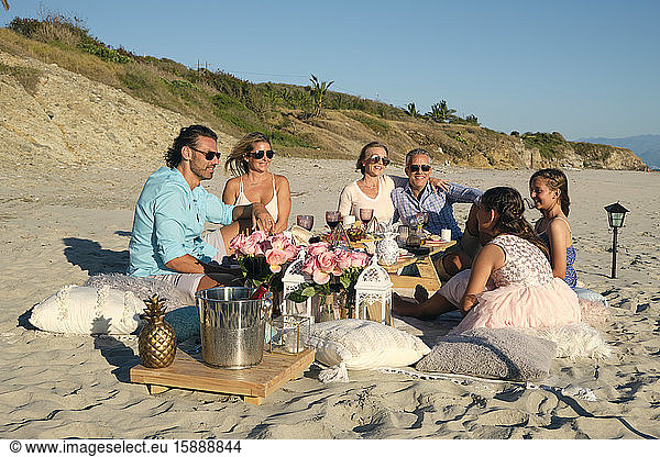 Family and friends enjoying picnic while sitting at beach against blue sky during sunset. Riviera Nayarit  Mexico