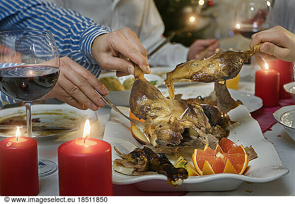 Family carving roasted duck for dinner