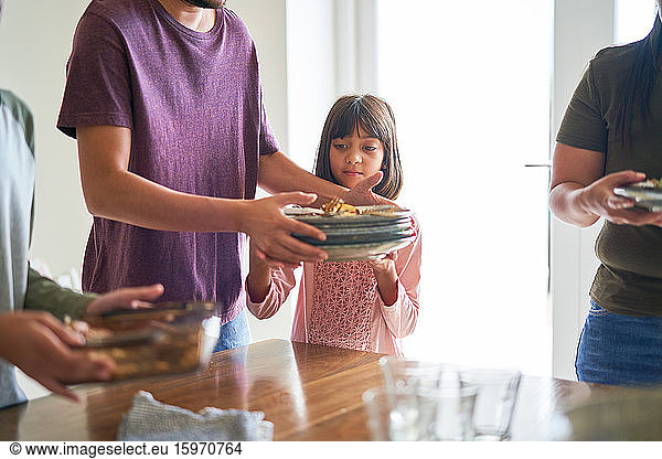 Family clearing dishes from dining table Family clearing dishes from ...