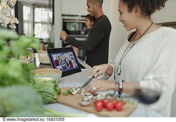 Family cooking and video chatting at digital tablet in kitchen