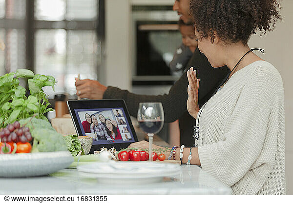 Family cooking and video chatting with friends on digital tablet