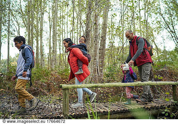 Family crossing footbridge on hike in woods