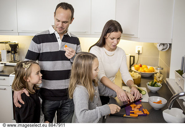 Family cutting vegetables at kitchen counter