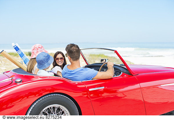 Family driving convertible to beach