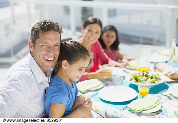 Family eating lunch at table on sunny patio