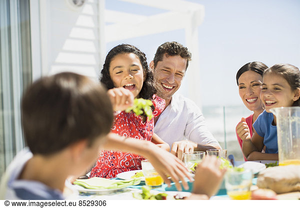 Family eating lunch at table on sunny patio