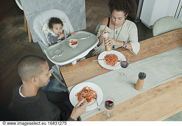 Family eating spaghetti at dining table and high chair