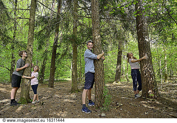 Family embracing tree while standing in forest