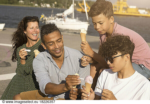 Family enjoying ice cream with each other while sitting on bench